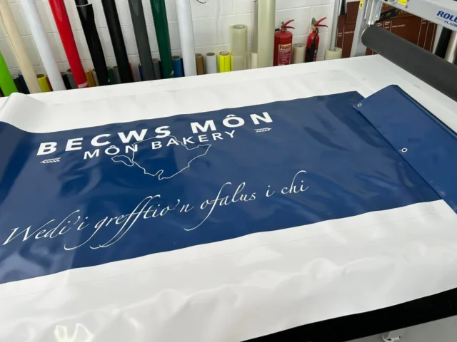 Printed banner for Becws Môn Bakery with bilingual Welsh and English branding